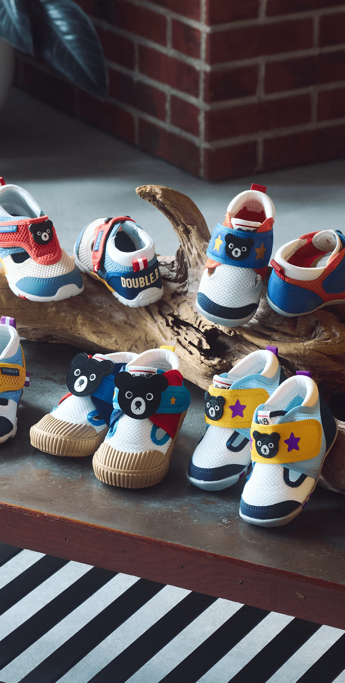 青いトレーナーを着て元気にポーズをとる、笑顔の子どもが白い壁の前に立っている